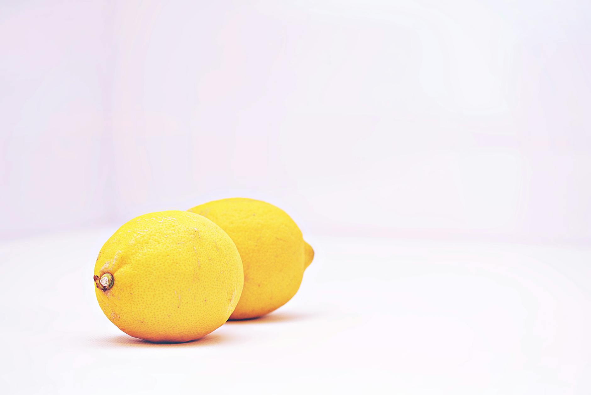 Two women laughing together with lemon slices, expressing joy and connection during playful moments