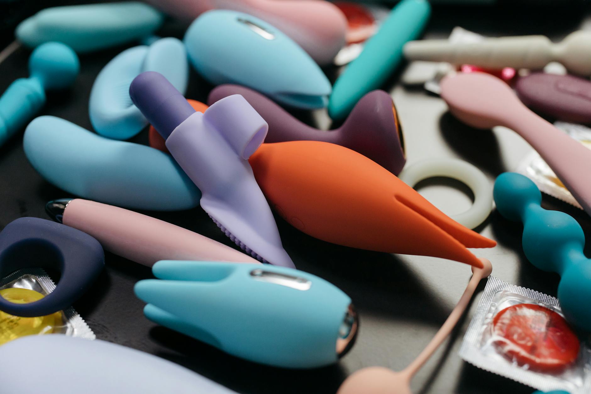 Hands holding pastel-colored silicone toys representing new couples exploring pleasure together