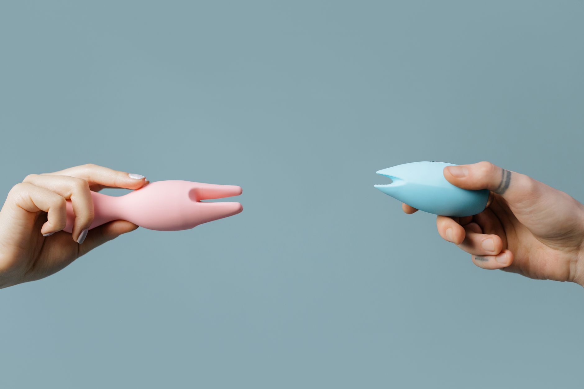 A blue silicone vibrator held in hand, demonstrating self-pleasure and clitoral stimulation.