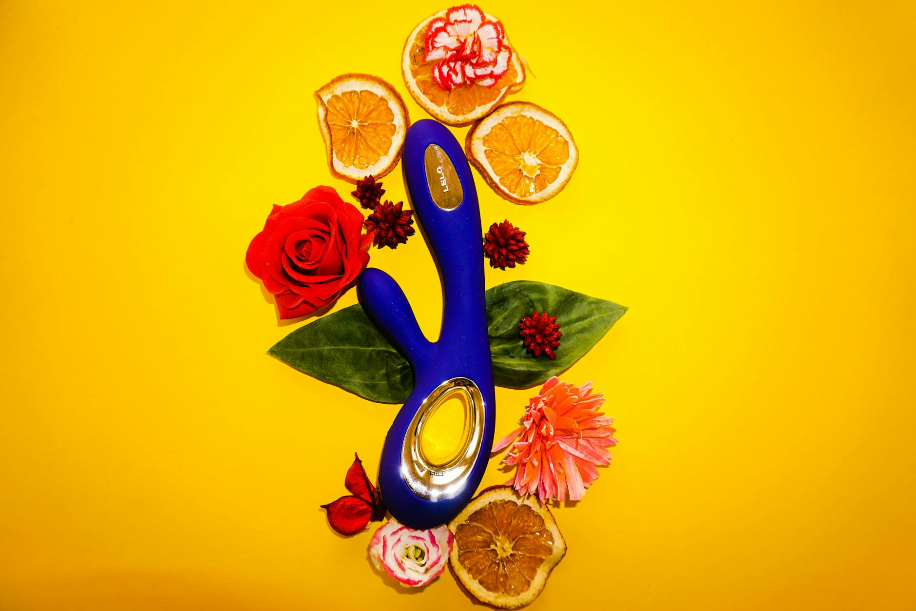 A blue silicone lemon vibrator held in hand against a solid purple background.